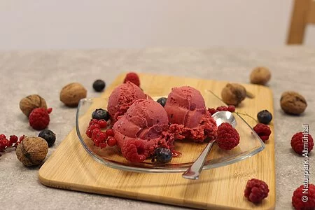 Eiskugeln drapiert auf Glasteller mit Früchten dekoriert