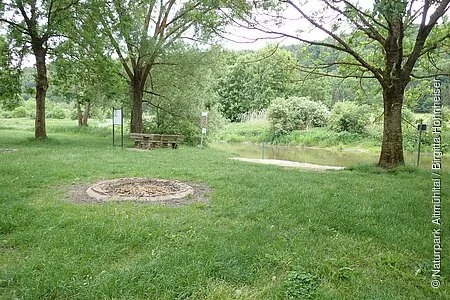Der Bootsrastplatz direkt an der Altmühl ist eine grüne Wiese mit einigen Bäumen als Schattenspender. Es gibt einige Feuerstellen und Sitzgelegenheiten.