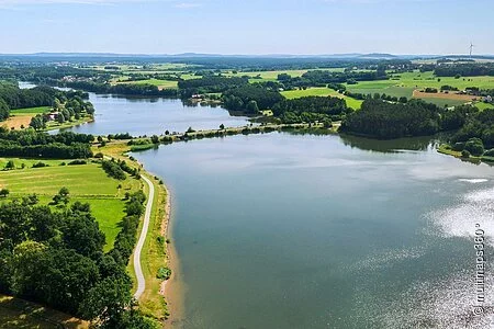 Luftbild von einem Teil des Rothsees. Der See ist umgeben von grünen Wiesen. Entlang des Ufers wachsen viele Bäume und Sträucher.