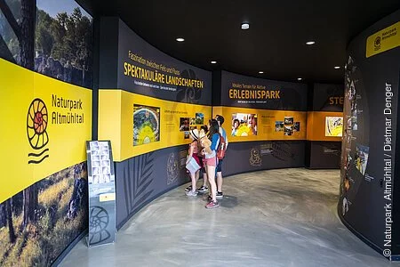 Eine Familie erforscht die Naturpark Altmühltal Ausstellung im Dinopark Denkendorf.