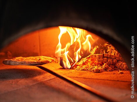 Baked tasty margherita pizza in Traditional wood oven in Naples restaurant, Italy. Original neapolitan pizza. Red hot coal.