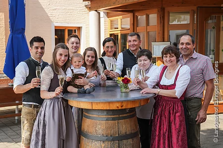 Das gesamte Team des Landgasthofes Euringer ist in Tracht gekleidet und steht hinter einem Stehtisch mit einem Glas Bier in der Hand.
