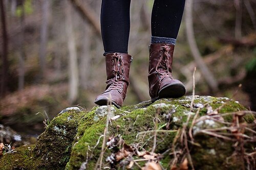 Stiefel im Wald Man sieht die Füße einer Person, in Wanderstiefeln, die auf einem bemoosten Stein im Waldl steht.