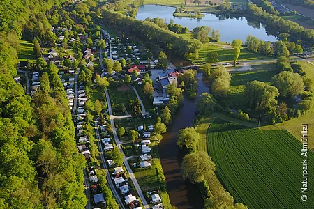 Der Campingplatz Kratzmühle mit vielen Wohnmobilen, -wagen von oben gesehen. Der Platz ist ein wenig in den Hang eingebettet und rechts ist schon der Kratzmühlsee.