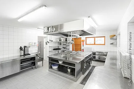 Die Großraumküche des Zeltplatzes ist in weiß und metall schlicht gehalten.