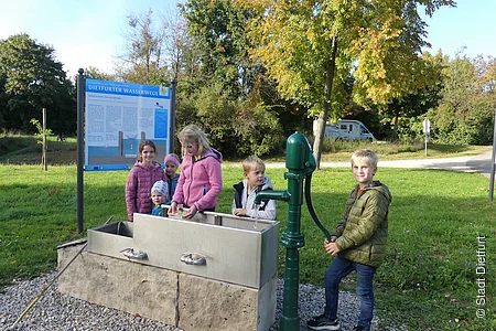 Schleusenmodell mit Schwengelpumpe am Schiffsanleger mit spielenden Kindern