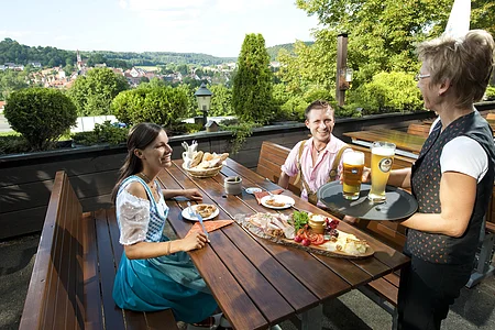 Das Foto zeigt den Biergarten des Hotel-Restaurant Bauer-Keller. Im Hintergrund sieht man einen Ausblick auf Greding.