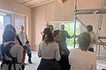 Architekt erklärt einer Gruppe die Holzmassivbauweise im neuen Kindergarten Kaldorf. Gruppenraum ist leer.