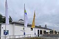 Das Gebäude des Freibads Beilngries von vorne. Es ist ein weißes Bungalow. Davor wehen Fahnen unter anderem vom Naturpark Altmühltal.