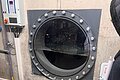 Sicht des Wassers, das über das Freibadbecken fließt. Rundes Bullauge, halb gefüllt mit Wasser.