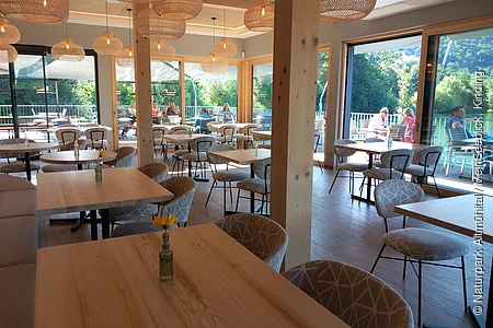 Das Restaurant ist mit Holzmöbel und Lampionlampen eingerichtet. Es ist hell und freundlich mit Blick auf den Kratmühlsee.