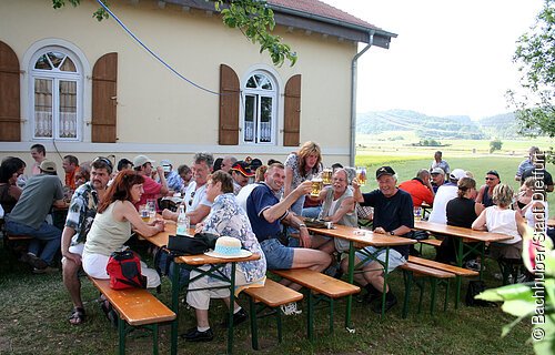 Feiernde Gäste auf Bierbänken vor dem Schleusenhaus