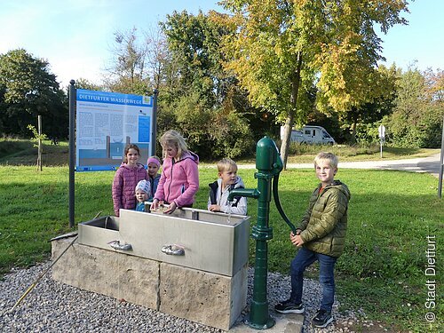 Schleusenmodell mit Schwengelpumpe am Schiffsanleger mit spielenden Kindern