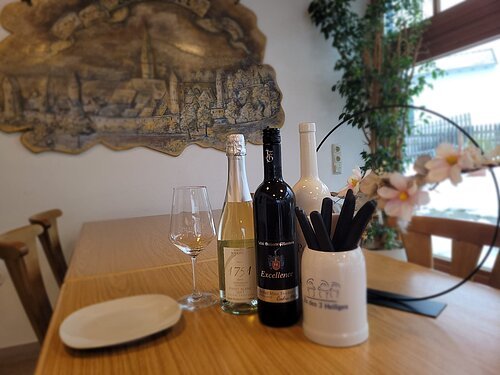 Verschiedene Weinflaschen stehen auf einem Tisch des Gasthofes. Im Hintergrund ein Wandrelief von Dietfurt.