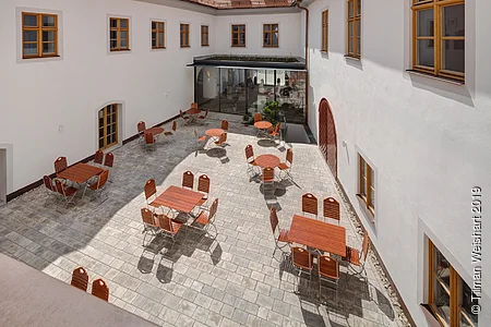 Blick in den Innenhof der Post Berching von oben auf ein gemütliches Ambiente mit Stühlen und Tischen eine Art Biergarten.