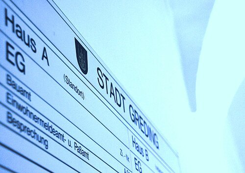 Hinweisschild mit Gebäude- und Abteilungsübersicht der Stadt Greding in blauem Licht.