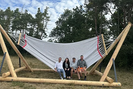 vier Erwachsene sitzen am Rand der Hängematte