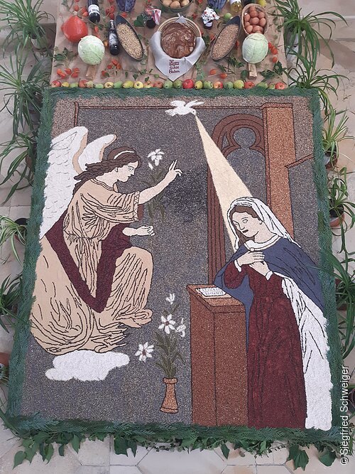 Das Körnerbild "Maria Verkündigung" zeigt wie der Engel Gabriel Maria erscheint. Es ist aus verschiedenen Körner in unterschiedlichen Farben "gemalt".