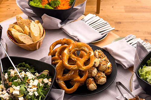 Gedeckter Tisch mit Brezen, Salate und anderen Köstlichkeiten